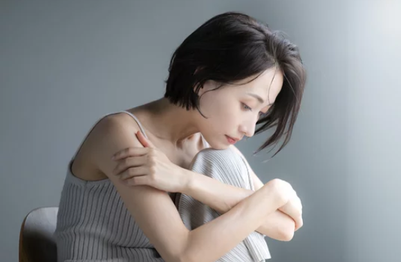灰色の背景でひとり沈み込む日本人女性 ─ Mani Padme 40代女性の人生転換期・誰にも言えない苦しさと魂の根本変革