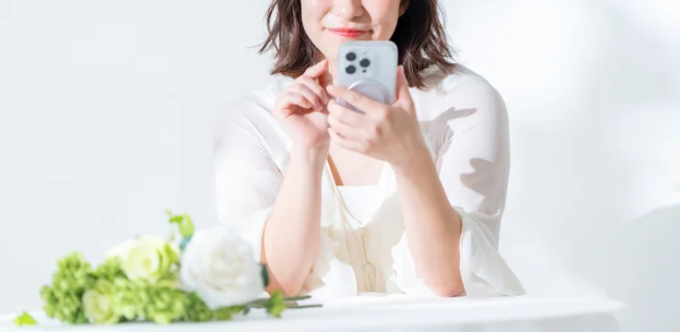 スマートフォンを両手で持ち微笑む日本人女性 ─ Mani Padme 40代女性が人生転換期に本当の自分を探すブログ