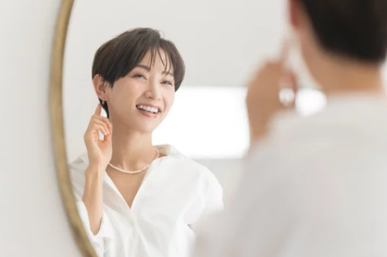 鏡の前で微笑む40代日本人女性 ─ Mani Padme 自己受容・魂の覚醒を経て本当の自分と出会う変容のイメージ